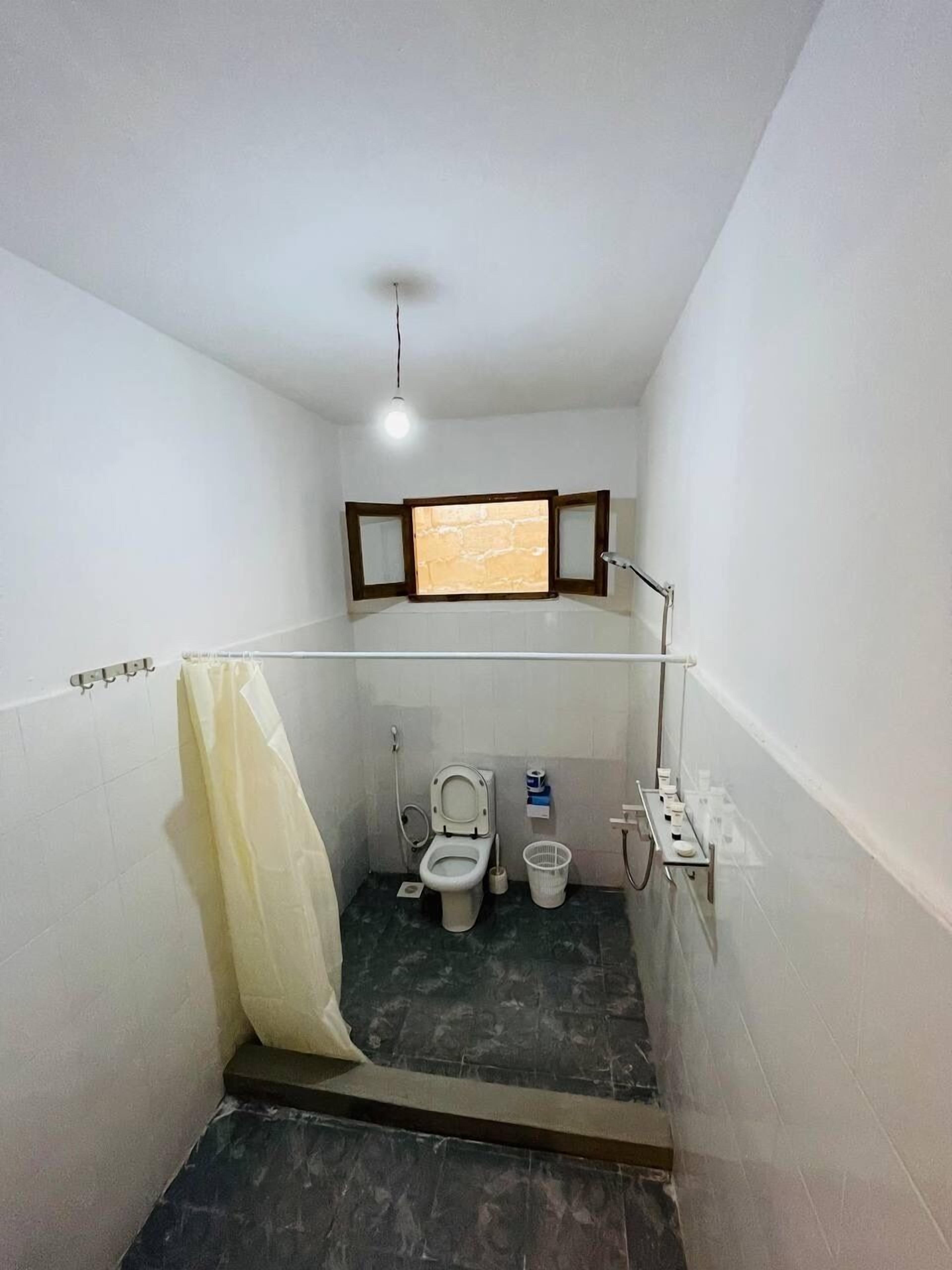 A small, narrow bathroom with a toilet, bidet, and a shower area.