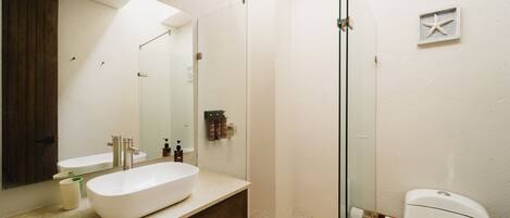 A modern bathroom with a large mirror, a white sink, and a glass shower enclosure.