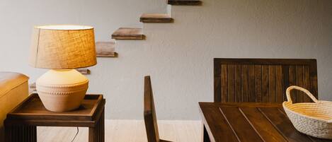 A wooden staircase with built-in lighting, a dining table with chairs, and a hanging light fixture.
