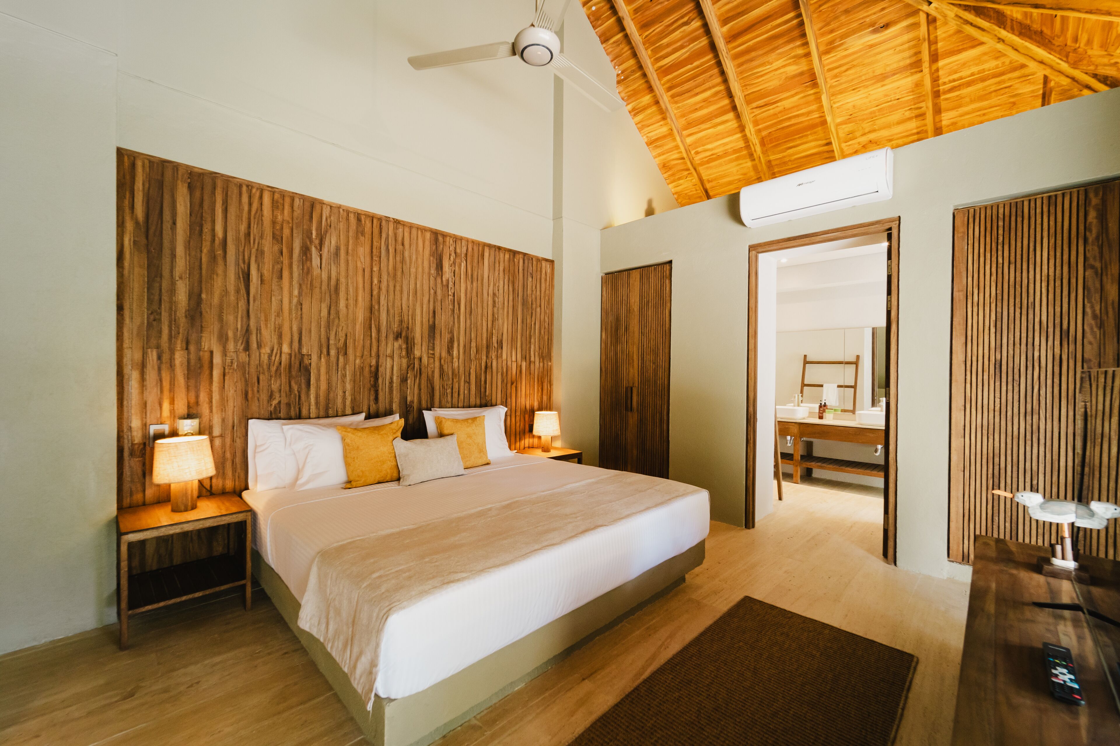A bedroom with a large bed, wooden headboard, bedside lamps, and a ceiling fan.