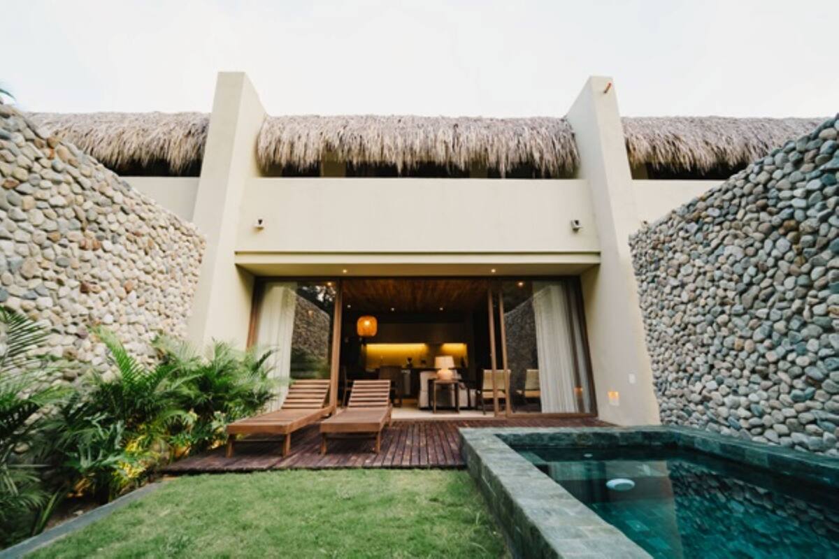 A resort with a thatched-roof entrance, a pool, and a well-maintained garden.