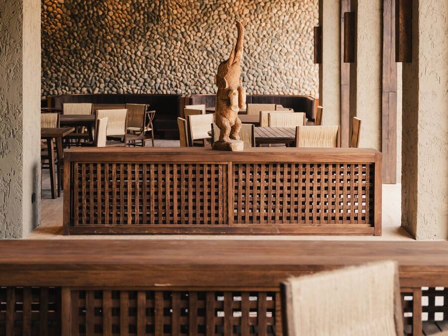Interior de restaurante con pared de piedra, mobiliario de madera y una lámpara colgante.
