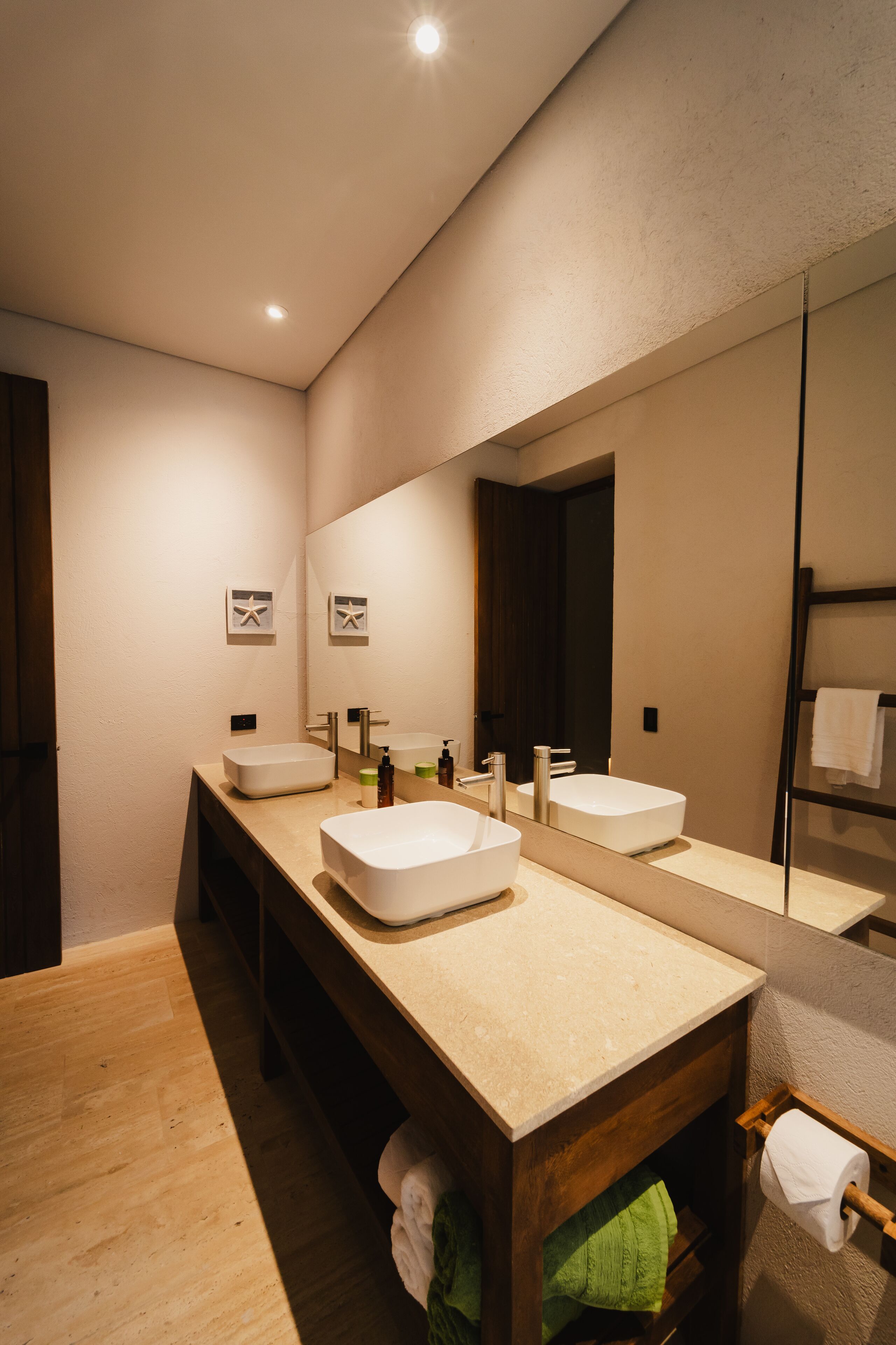 A modern bathroom with two sinks, a large mirror, and a wooden vanity.