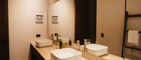 A modern bathroom with two sinks, a large mirror, and a wooden vanity.