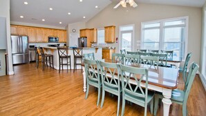 A spacious kitchen with wooden cabinets, a dining area with a large table and chairs, and a ceiling fan.