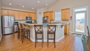 A modern kitchen with wooden cabinets, stainless steel appliances, and a central island with bar stools.