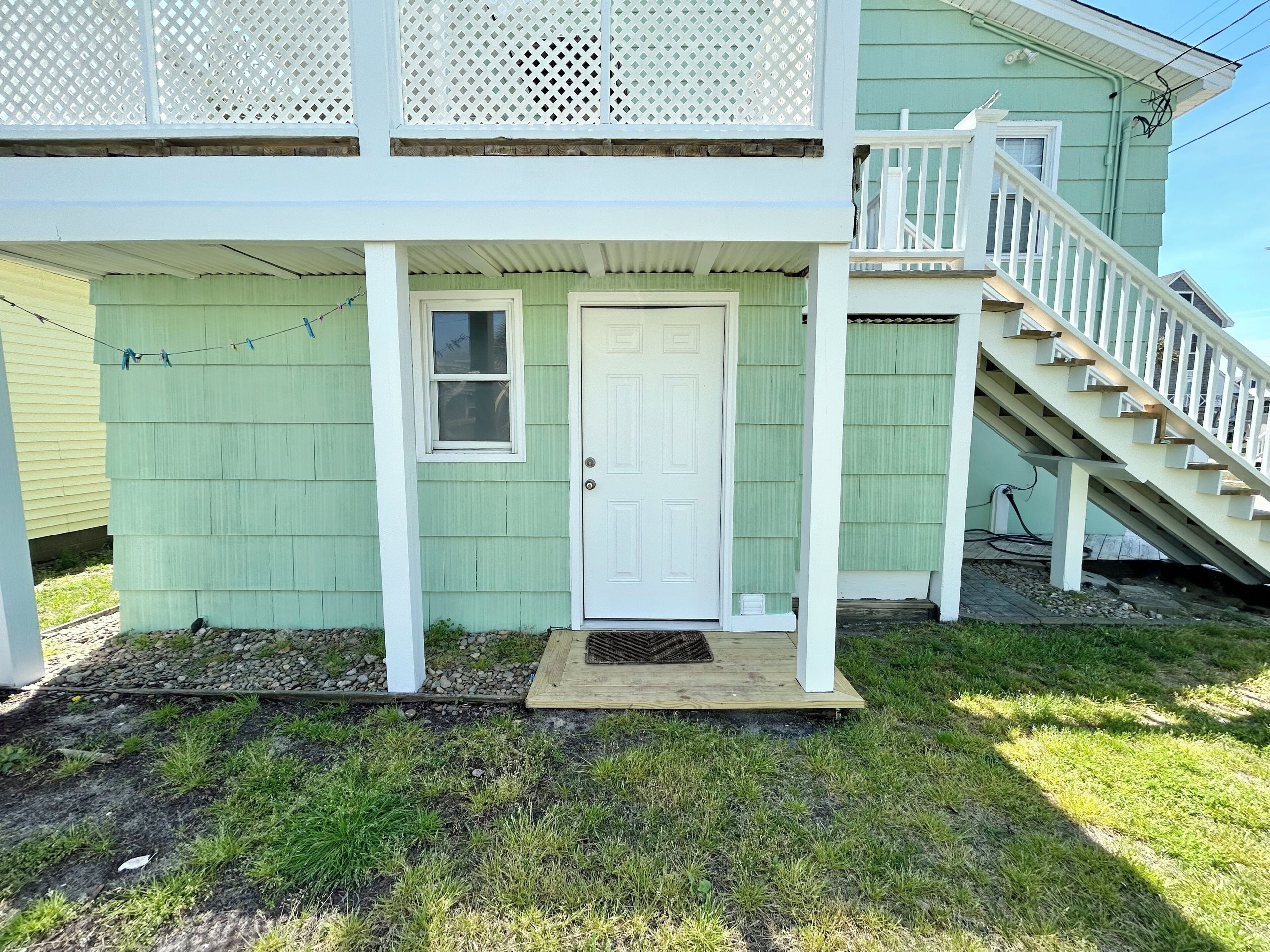 A two-story house with a white porch, a front door, and a staircase leading to the upper level.