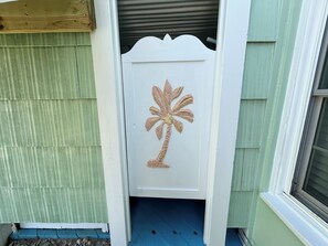 A white door with a palm tree design, a green exterior wall, and a blue floor. - Beach Life Up, Oceanview Duplex in Atlantic Beach, NC! (Atlantic Beach)