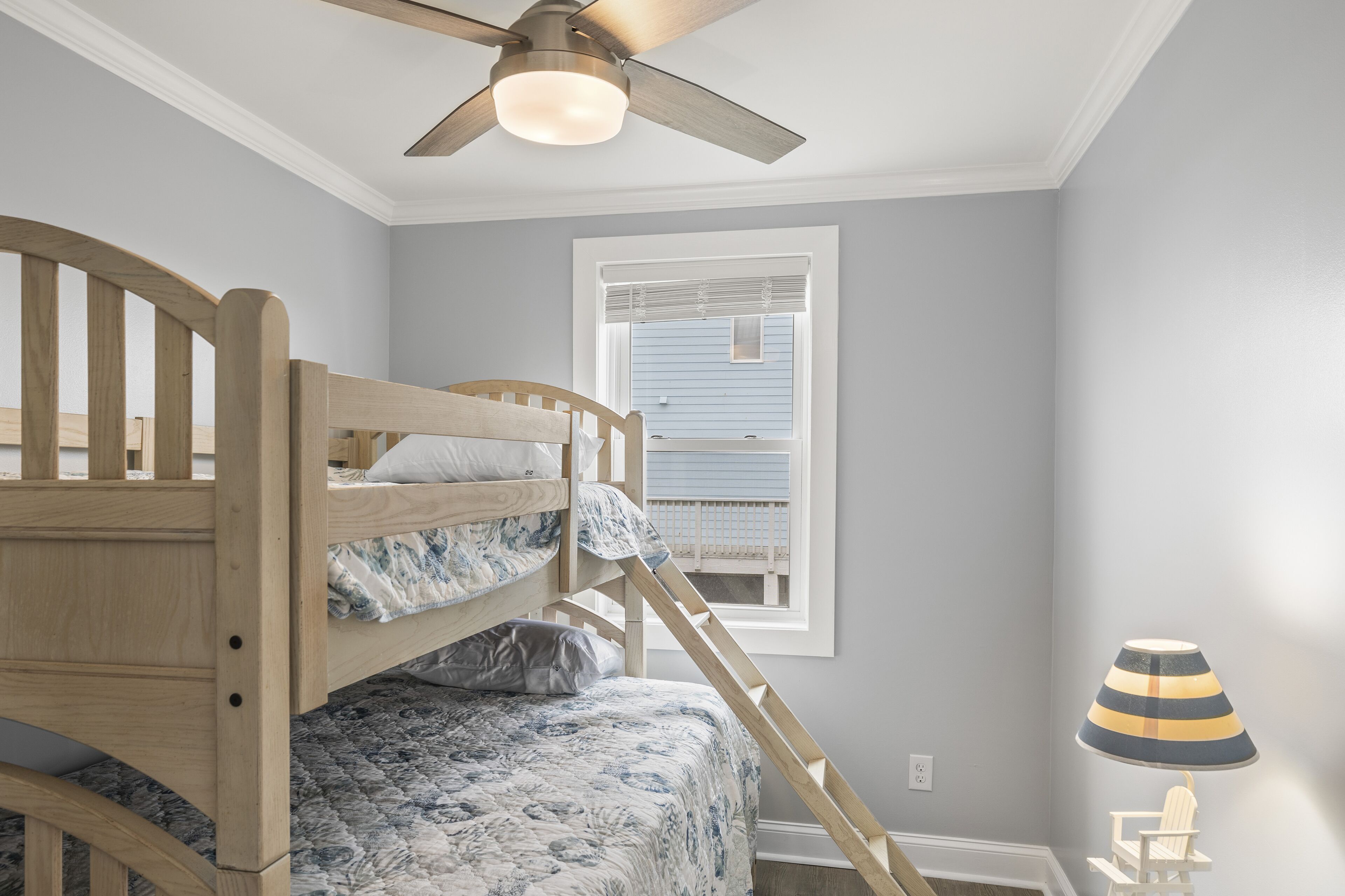 Ein Schlafraum mit Etagenbetten, Deckenventilator, Fenster mit Jalousien und einer Lampe.