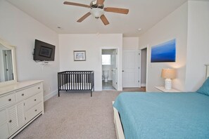 A bedroom with a bed, a crib, a television, and a ceiling fan. - Beached, Almost Oceanfront House in Emerald Isle, NC! (Emerald Isle)