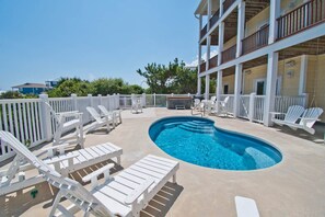 A pool area with white lounge chairs and a pool. - Beached, Almost Oceanfront House in Emerald Isle, NC! (Emerald Isle)