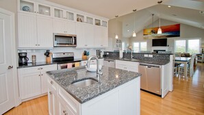 Cocina moderna con armarios blancos, encimeras de granito y una isla central con fregadero.