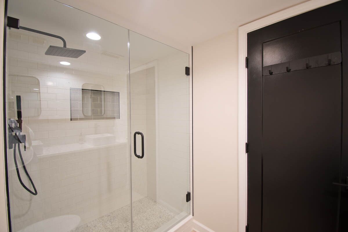 A glass-enclosed shower area with a handheld showerhead and a wall-mounted faucet.