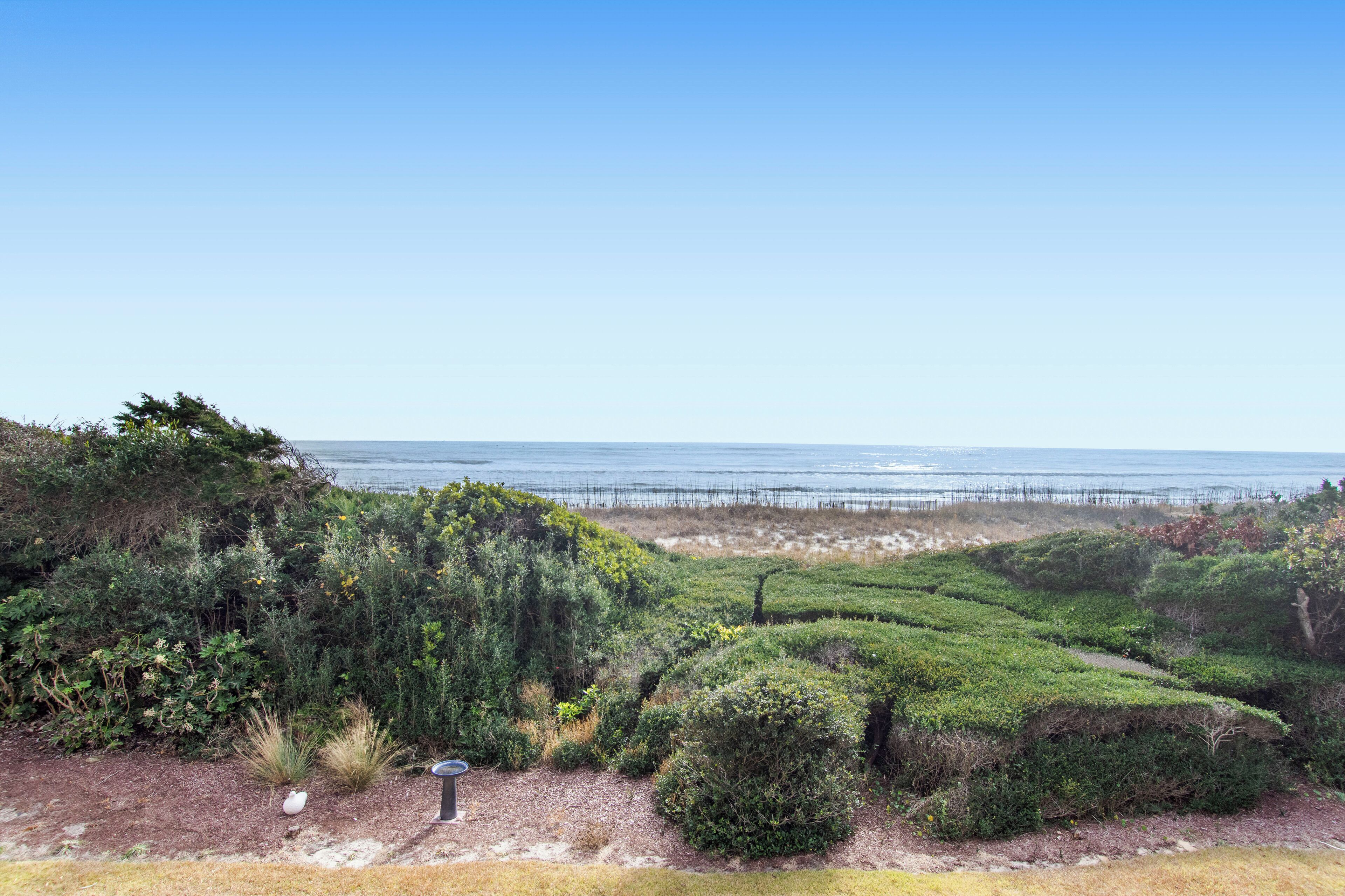 Un paisaje costero con una vista despejada del océano y un muelle de madera que se adentra en el agua.