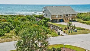 A two-story house with a balcony overlooking the ocean, surrounded by lush greenery. - Bermuda House, Almost Oceanfront House in Emerald Isle, NC! (Emerald Isle)