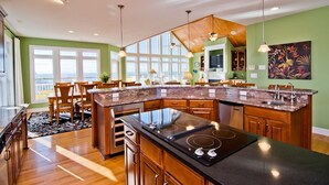 A modern kitchen with a large island, wooden cabinets, and a view to the outside. - Bermuda House, Almost Oceanfront House in Emerald Isle, NC! (Emerald Isle)