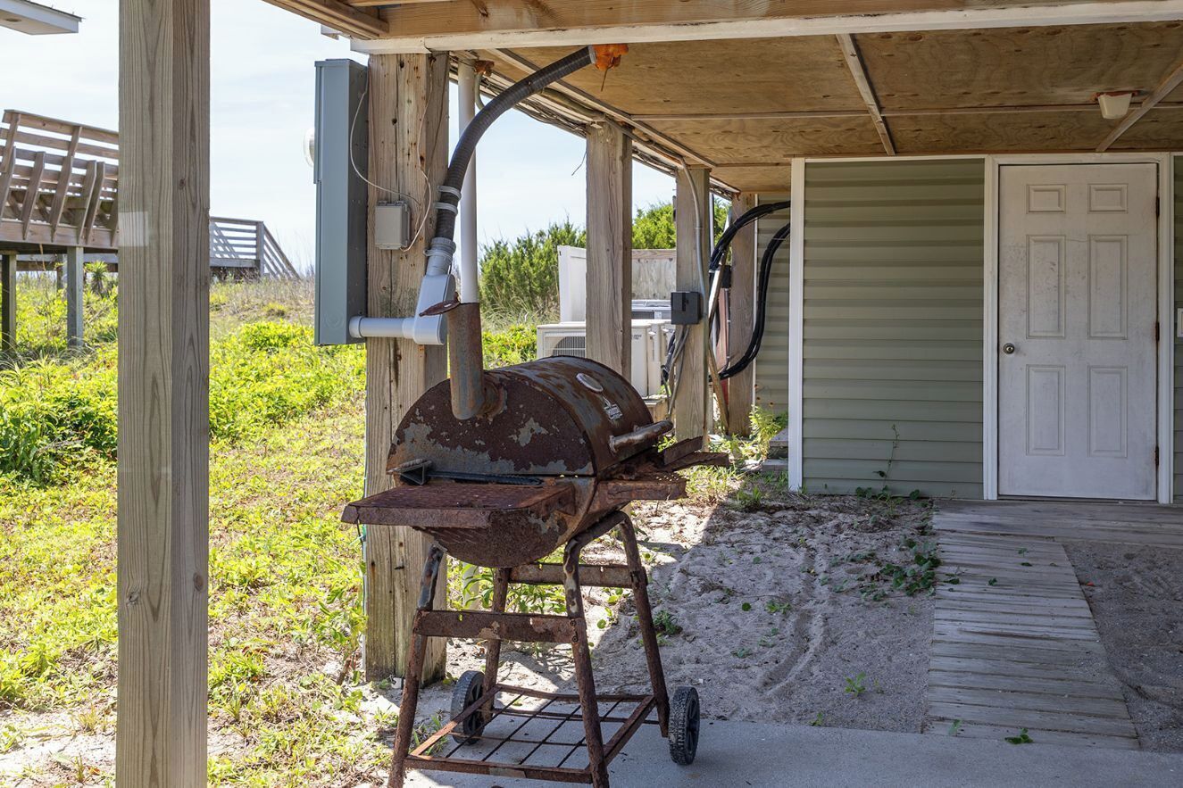 A rustic outdoor grill setup on a wooden deck, a door, and a covered area with a bench.