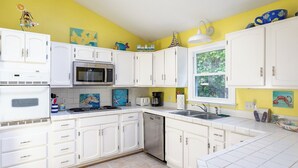 A kitchen with white cabinets, a microwave, a stove, and a sink.