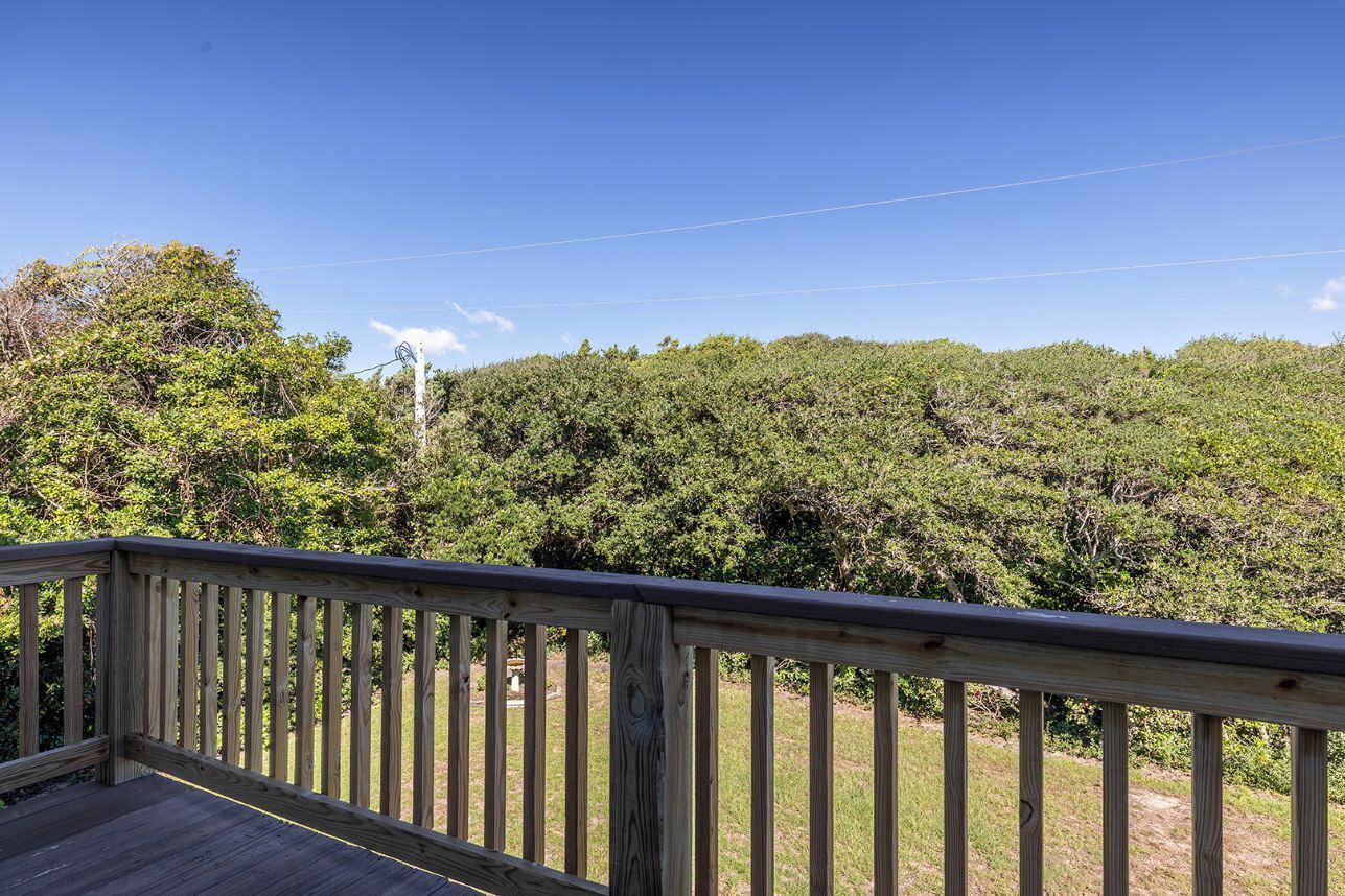 A wooden deck with a clear view of a forested area in the background.