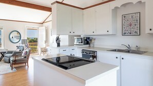Una cocina moderna con armarios blancos, una isla central y un comedor con una silla y una mesa.