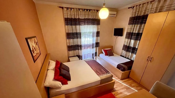 A hotel room with two beds, a desk, a chair, a wardrobe, and a TV. - Algo Hotel (Tirana)