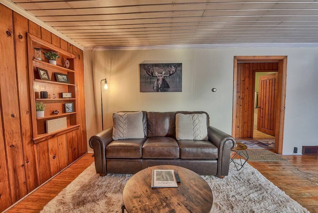 A cozy living room with a leather sofa, a round coffee table, and a wooden bookshelf.