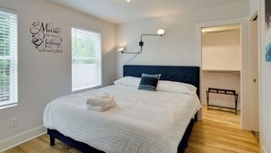 A bedroom with a bed, a wall-mounted light, and a ceiling fan.
