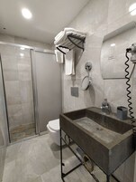 A modern bathroom with a glass shower enclosure, a toilet, a sink with a mirror, and a towel rack.
