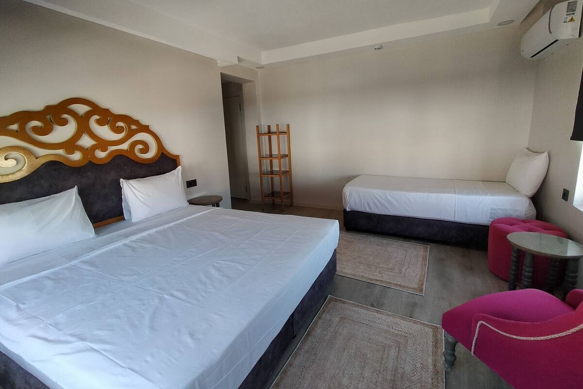 A hotel room with two beds, a small table, a red chair, and a wooden ladder.