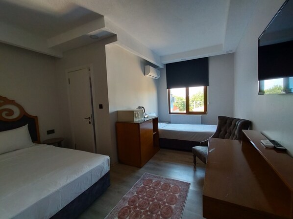 A hotel room with a bed, a desk, a chair, a radiator, and a window with a view. - Gala Edirne (Edirne)