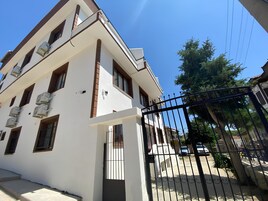A multi-story building with a white facade, brown window frames, and air conditioning units.