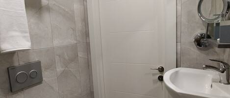 A bathroom with a toilet, a sink with a mirror, and a towel rack.