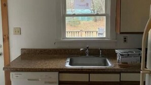 A kitchen with a window, a sink, and cabinets.