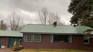 A single-story building with a green metal roof and a front porch.