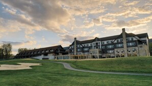 A modern hotel with multiple floors and a prominent chimney, situated on a grassy slope with a clear sky. - Relaxing & Rejuvenating Retreat w/Hot tub, Pool, Sauna, & Games for family+pets (Berkeley Springs)