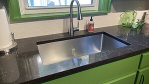 A kitchen with a stainless steel sink, green cabinets, and a window above the sink. - The Vandalia House - Midcentury Rodeo Meets Midtown, University of Tulsa, and Expo Center (Tulsa)