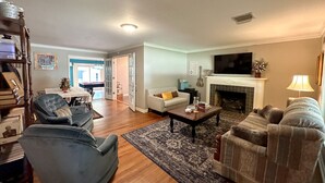 A living room with a fireplace, a television, and a dining area with a table and chairs. - The Vandalia House - Midcentury Rodeo Meets Midtown, University of Tulsa, and Expo Center (Tulsa)