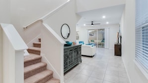 A spacious living area with a staircase, a white sofa, and a cabinet.
