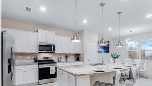 A modern kitchen with white cabinets, stainless steel appliances, and a granite countertop island.
