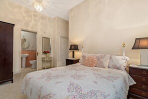 A bedroom with a large bed, a bedside table with a lamp, a dresser, and a mirror on the wall. - Bryn Y Mor - Swimming Pool and  Sea Views (Tenby)