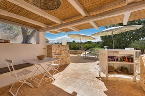 Une terrasse extérieure avec un mur en pierre, une table avec des chaises et des parasols.