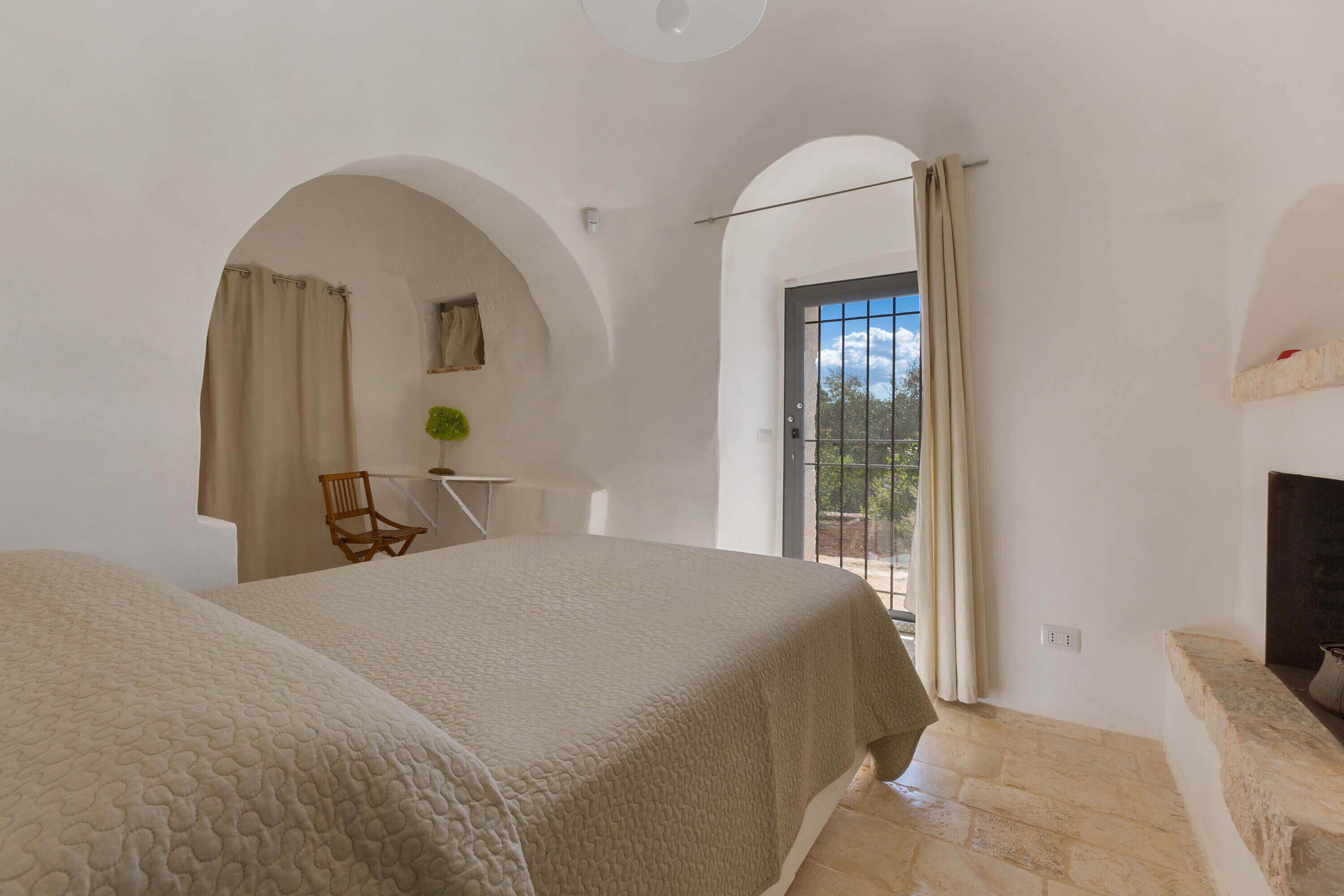 A bedroom with two beds, a small table, a chair, and a fireplace.