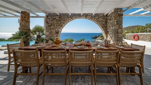 A table set for six with a stone archway, overlooking a pool and the sea. - Sanarte  Villas Mykonos (Mykonos)