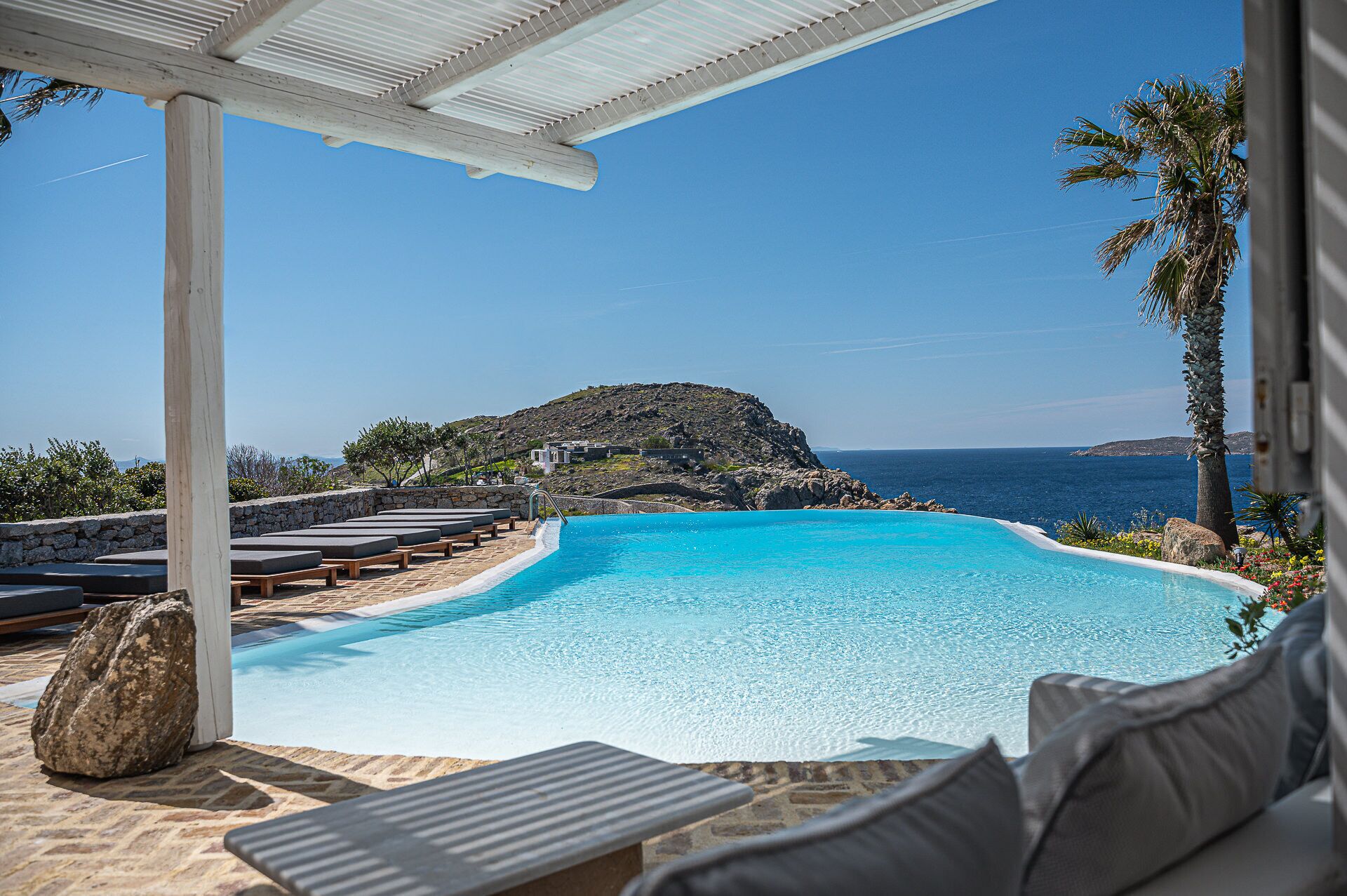 A pool with lounge chairs and a view of the sea.