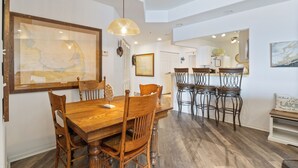 Un comedor con una mesa y sillas de madera, una lámpara colgante y un mapa enmarcado en la pared.