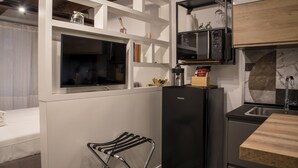 A compact kitchen with a black refrigerator, a microwave, and a sink. There is a small seating area with a chair and a table. - Maritè Apartment (Naples)