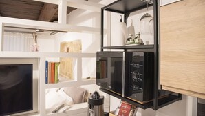 A modern kitchen with a built-in microwave, a coffee maker, and a wine glass on a shelf. - Maritè Apartment (Naples)