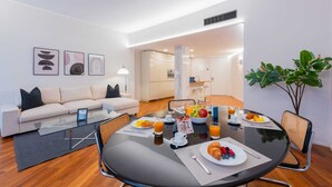 Ein modernes Wohnzimmer mit einer Couch, einem Glastisch und einem Essbereich mit einem runden Frühstückstisch.