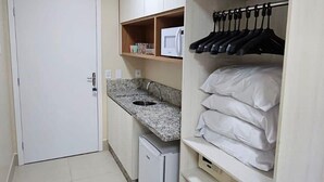 A compact kitchen with a refrigerator, microwave, and granite countertop. - Apartamento acesso ao diRoma Acqua Park (Caldas Novas)