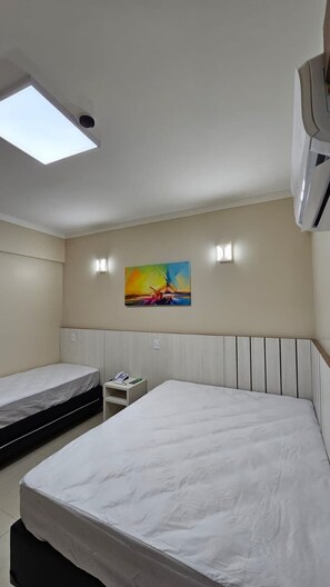 A hotel room with two beds, a skylight, a painting on the wall, and a small bedside table with a phone. - Apartamento acesso ao diRoma Acqua Park (Caldas Novas)